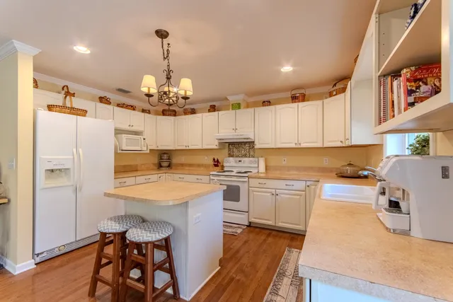 a kitchen with a refrigerator a sink dishwasher a dining table and chairs with wooden floor