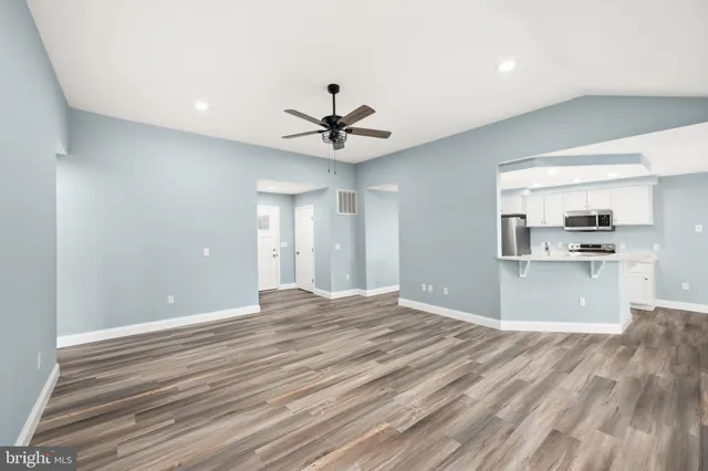 a view of kitchen and empty room with wooden floor