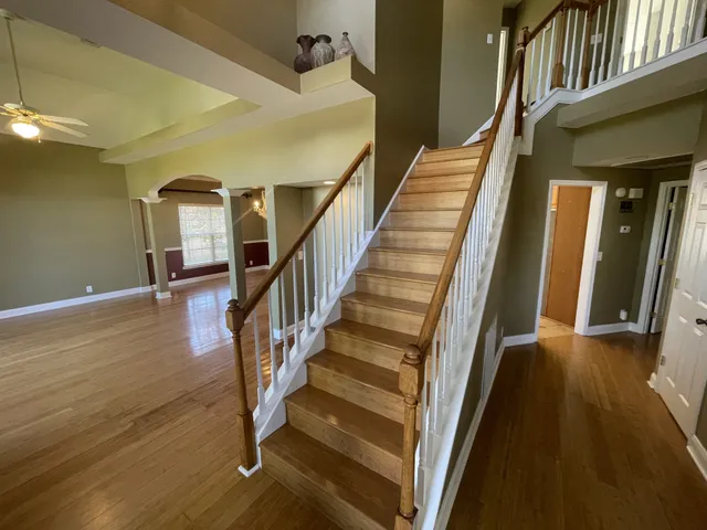 a view of staircase with lots of frames on wall and wooden floor