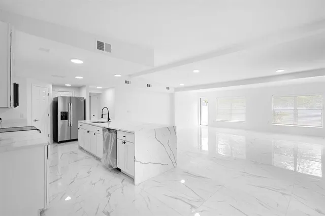 a large white kitchen with white cabinets and a refrigerator