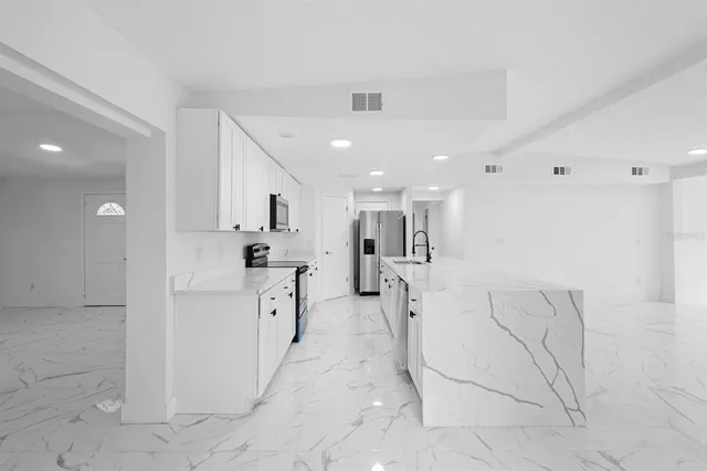 a large white kitchen with white cabinets and stainless steel appliances