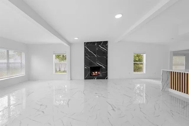 an empty room with windows and fireplace