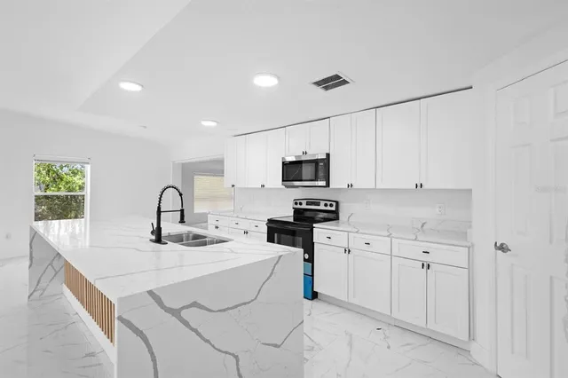 a kitchen with stainless steel appliances kitchen island granite countertop a sink a stove and cabinets