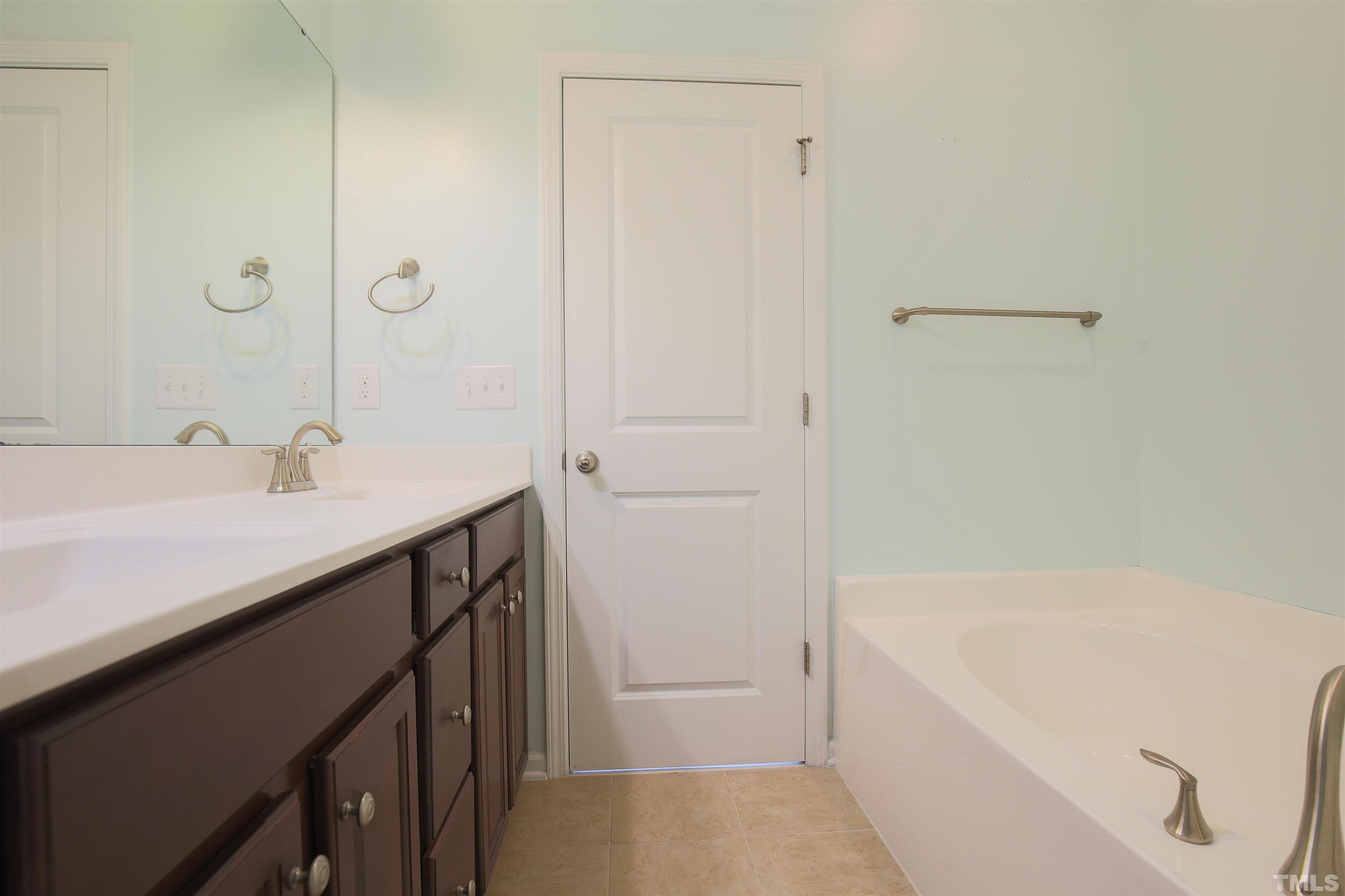 696 Wickham Ridge Road Apex, NC 27539 - Photo 16 of 24 a bathroom with a tub sink vanity and mirror
