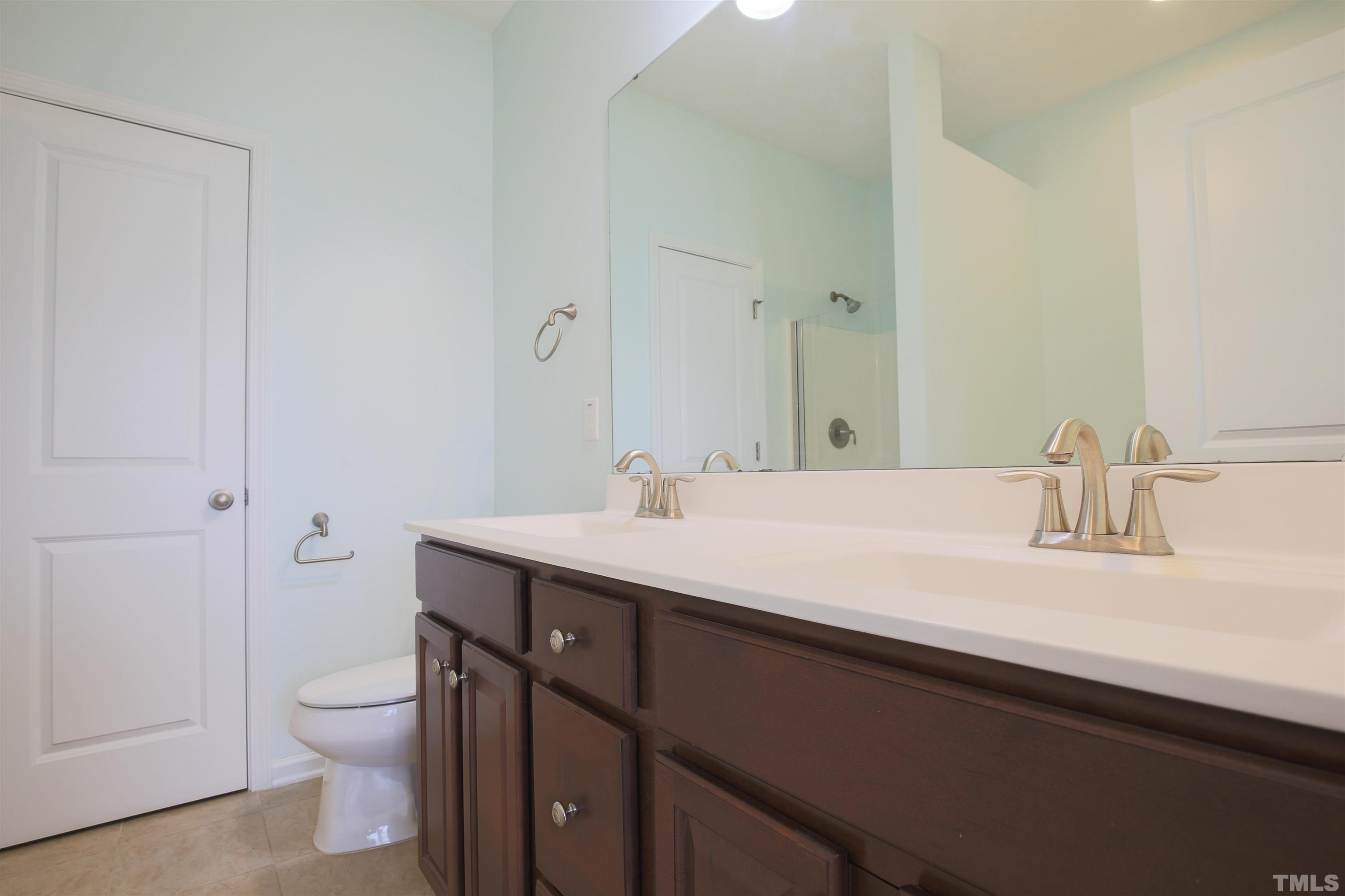696 Wickham Ridge Road Apex, NC 27539 - Photo 4 of 24 a bathroom with a granite countertop sink a toilet and a mirror