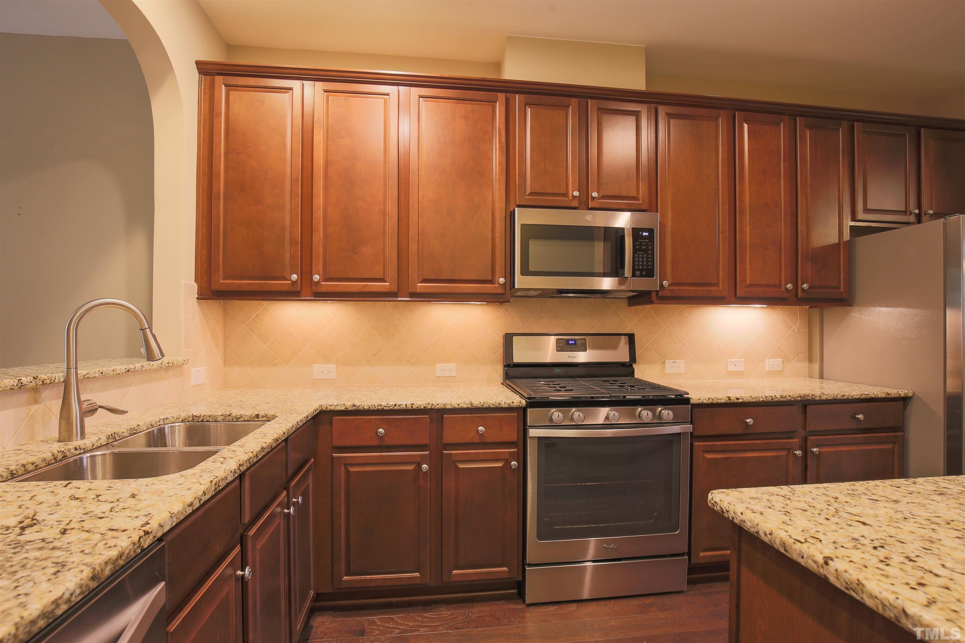 696 Wickham Ridge Road Apex, NC 27539 - Photo 8 of 24 a kitchen with granite countertop wooden cabinets and a stove top oven