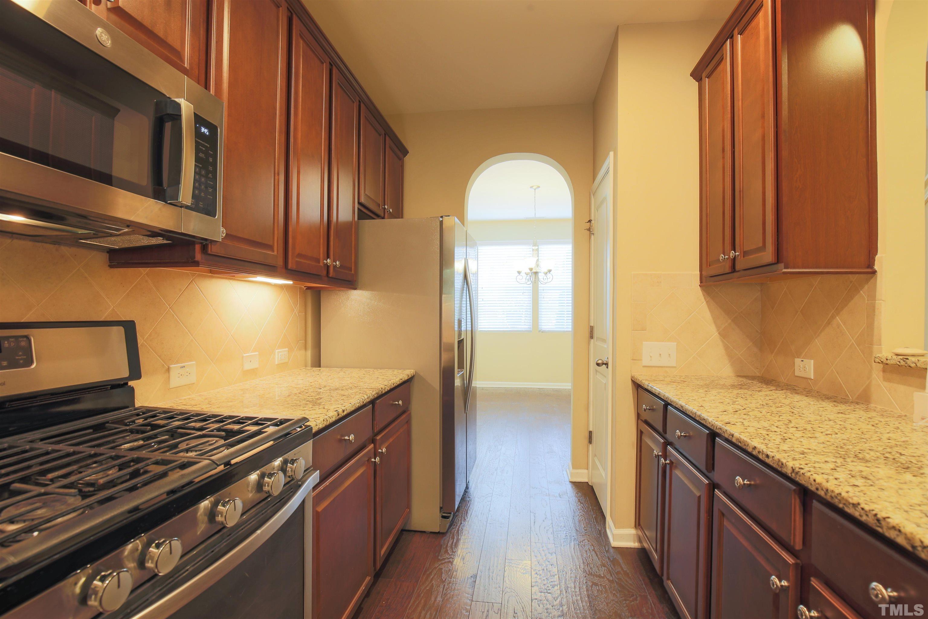 696 Wickham Ridge Road Apex, NC 27539 - Photo 9 of 24 a kitchen with stainless steel appliances granite countertop a stove a sink and a microwave