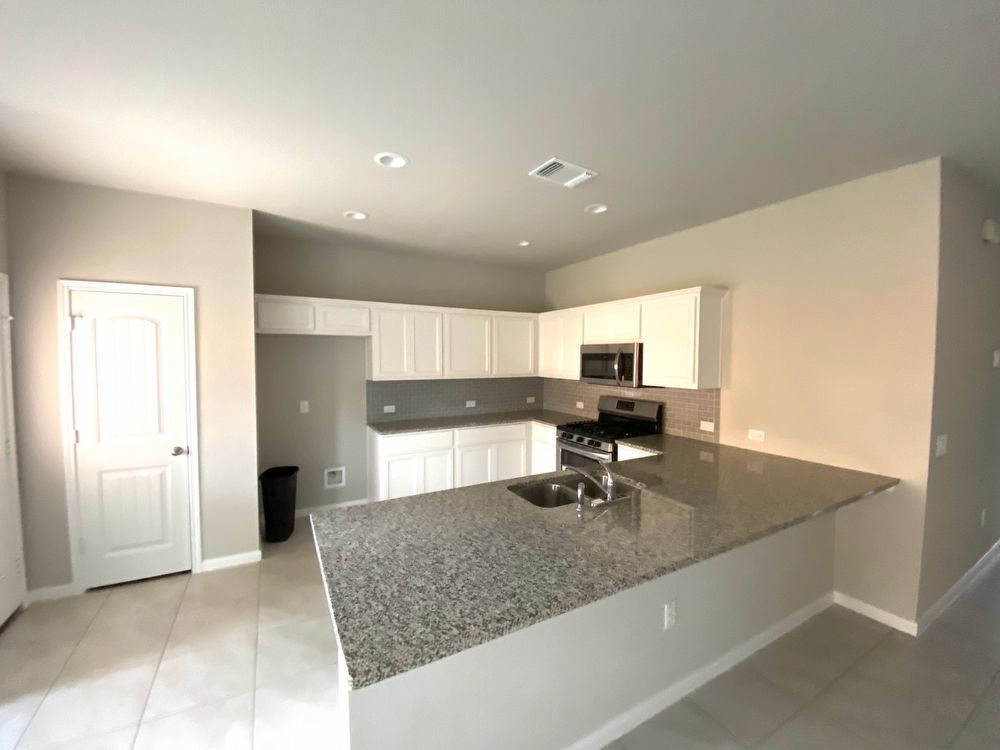 6713 Ranchito Drive Austin, TX 78744 - Photo 7 of 12 Kitchen featuring white cabinetry, a peninsula, stainless steel appliances, dark stone counters, and light tile patterned flooring