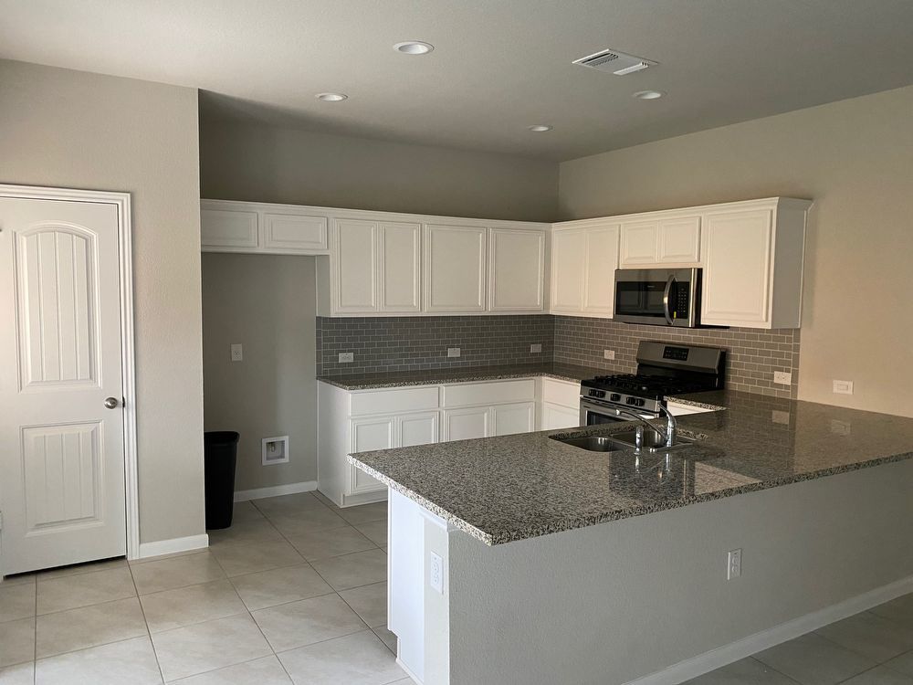 6713 Ranchito Drive Austin, TX 78744 - Photo 8 of 12 Kitchen with dark stone counters, a peninsula, white cabinetry, decorative backsplash, and stainless steel appliances
