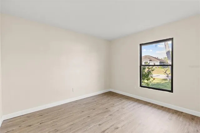 an empty room with wooden floor and window