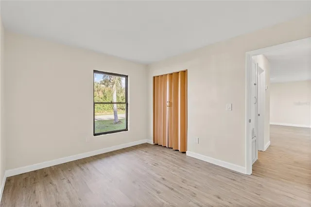 an empty room with wooden floor and window