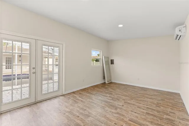 a view of an empty room with wooden floor and windows