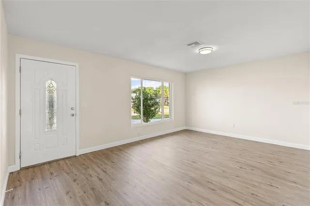 an empty room with wooden floor and windows