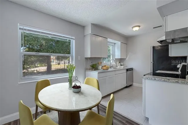 a kitchen with stainless steel appliances granite countertop a stove a kitchen island a table and a sink