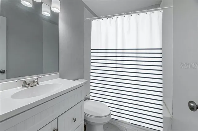 a bathroom with a sink a toilet and shower curtain