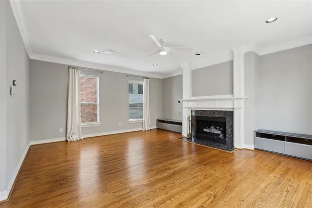 a view of an empty room with wooden floor fireplace and a window