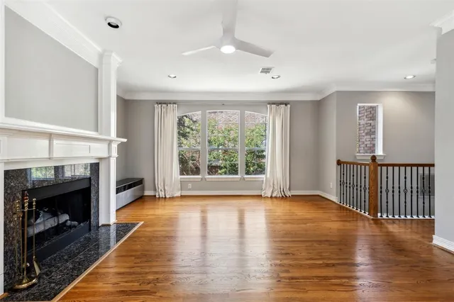 a view of an empty room with wooden floor fireplace and a window