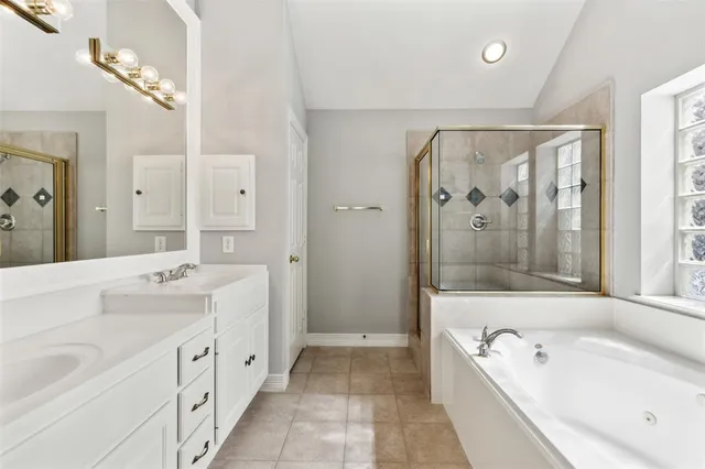 a spacious bathroom with a tub a double vanity sink a mirror a shower and vanity