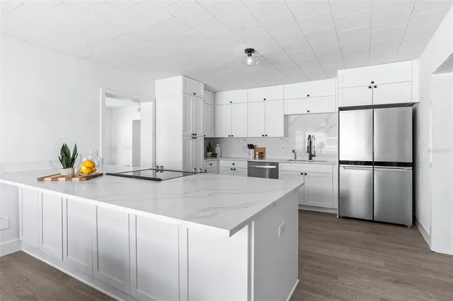 a kitchen with a sink a refrigerator and white cabinets