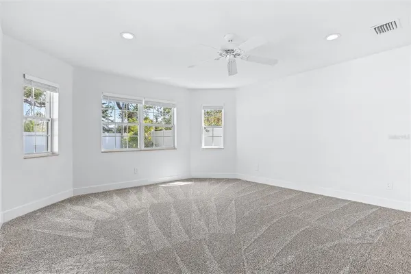 an empty room with windows and fan