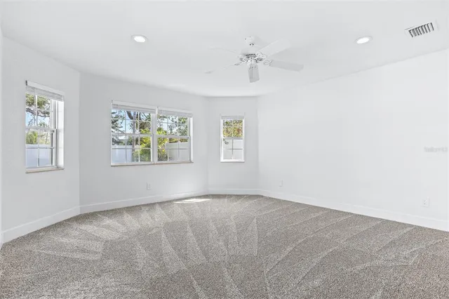 an empty room with windows and fan