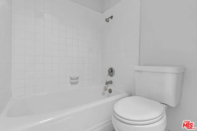 a white toilet and tub sitting next to a white cabinet