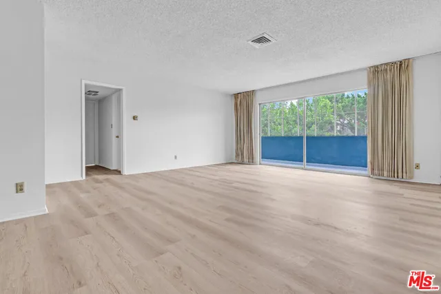 an empty room with large windows and a backyard