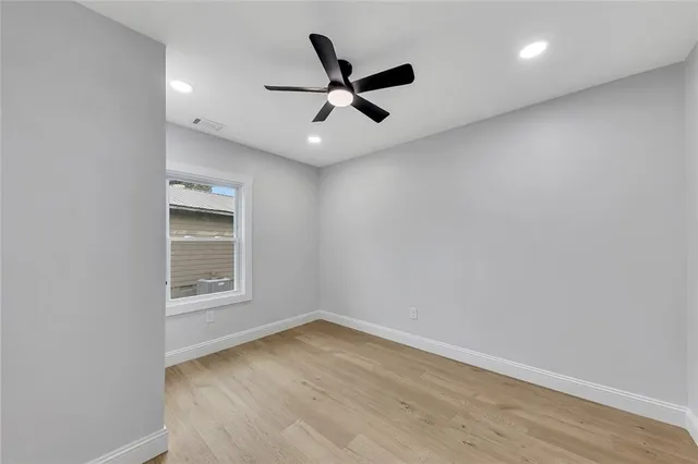 an empty room with a ceiling fan and wooden floor