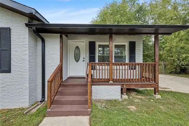 a view of a brick house with wooden deck and furniture