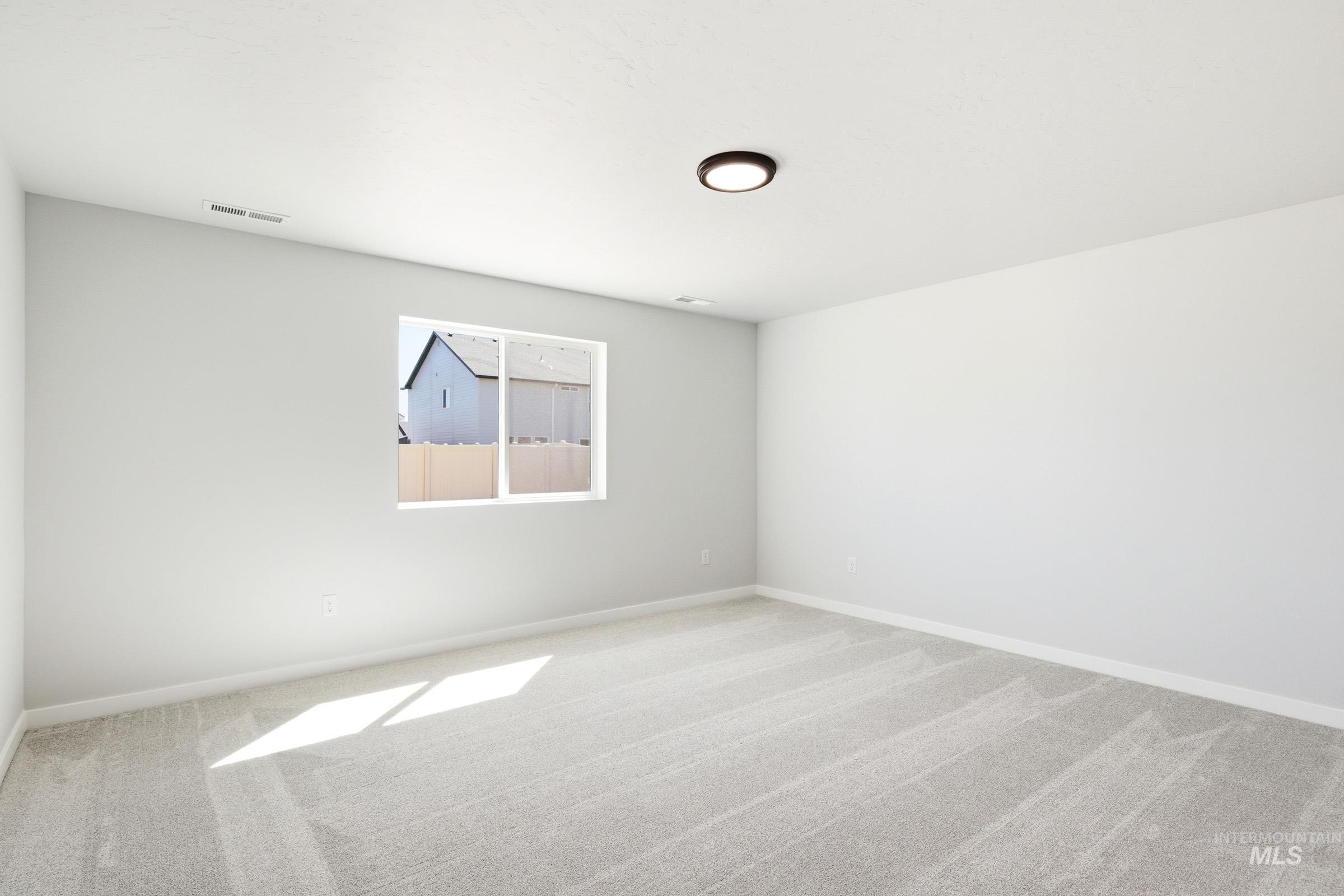 12817 Decatur Street Nampa, ID 83651 - Photo 16 of 19 Spacious room featuring light gray carpeting, a large window, and a flush-mount ceiling light fixture
