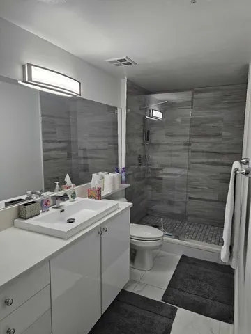 a bathroom with a sink a toilet a mirror and shower