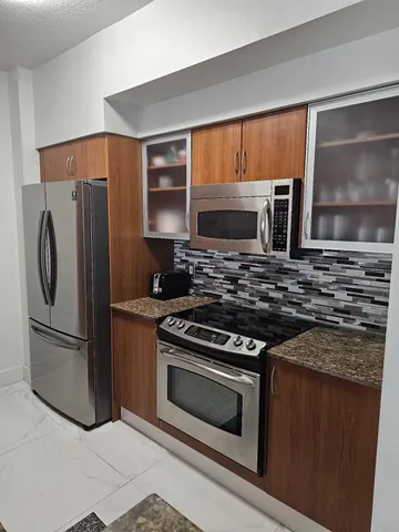 a kitchen with granite countertop a stove microwave and refrigerator