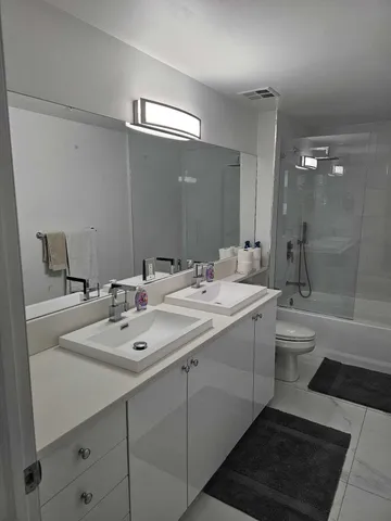a bathroom with a double vanity sink mirror and toilet