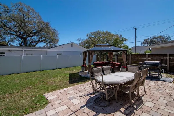 a couch sitting in a patio with a table and chairs under an umbrella