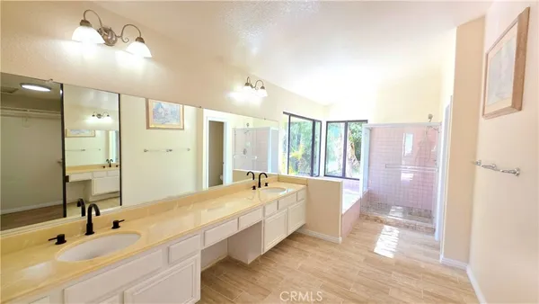 a spacious bathroom with a double vanity sink a large mirror and a bathtub