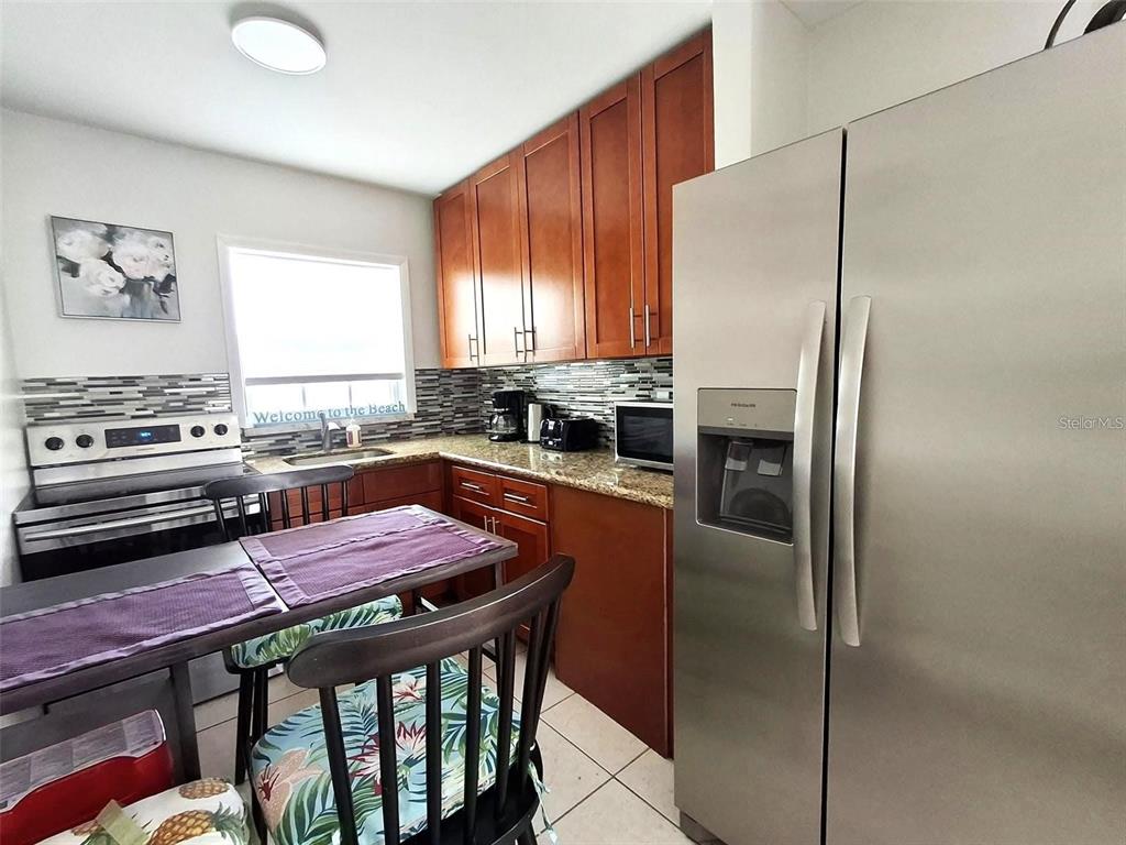 113 174th Avenue East Redington Shores, FL 33708 - Photo 5 of 16 a kitchen with stainless steel appliances granite countertop a stove a refrigerator and a stove top oven