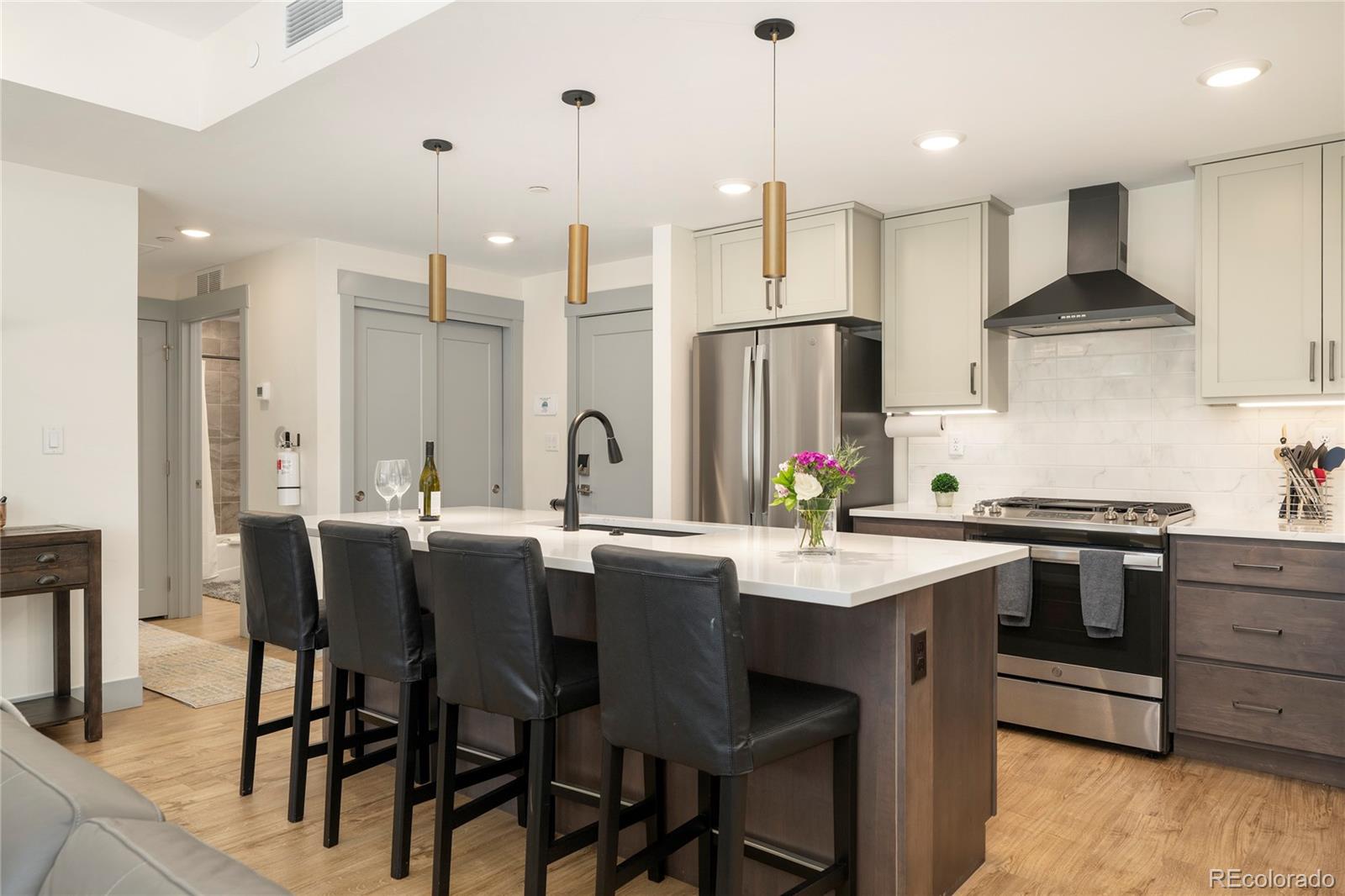 144 Ski Idlewild Road, Unit 2203 Winter Park, CO 80482 - Photo 13 of 45 a kitchen with stainless steel appliances kitchen island granite countertop a stove a sink a oven a dining table and chairs with wooden floor