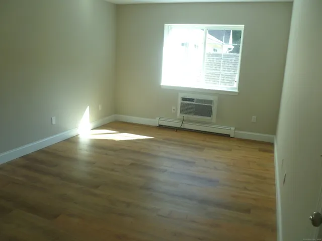 a view of an empty room with wooden floor and closet