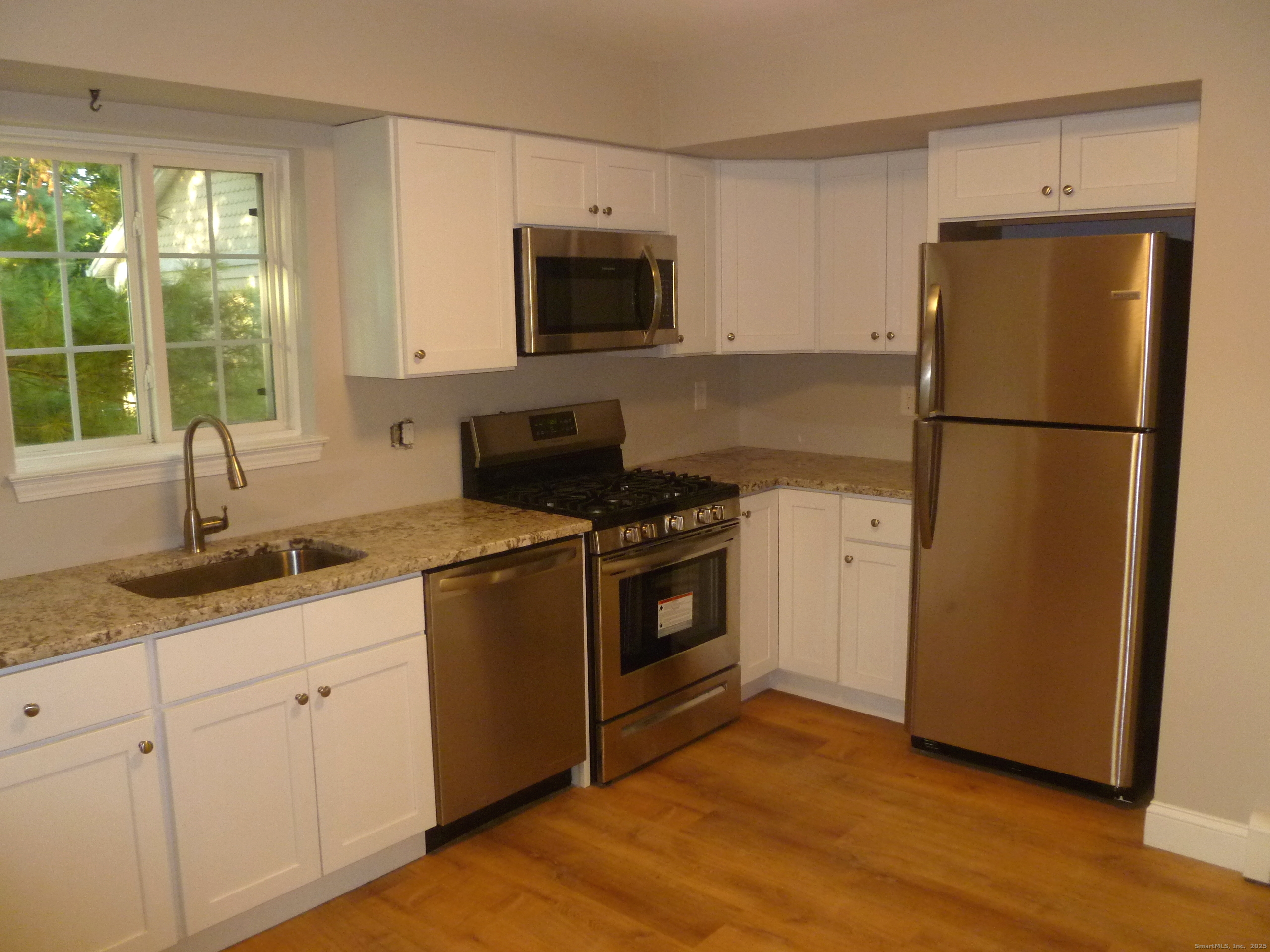 2955 Madison Avenue, Unit 46 Bridgeport, CT 06606 - Photo 9 of 29 a kitchen with granite countertop white cabinets and refrigerator