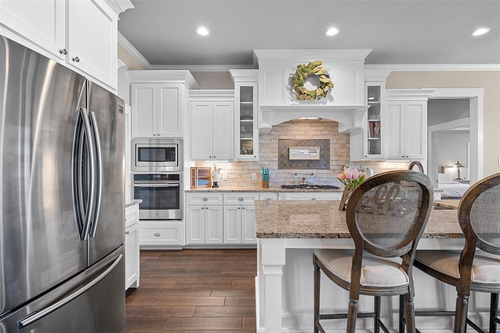 23 Independence Trail Waco, TX 76708 - Photo 5 of 35 Gourmet kitchen featuring white cabinetry, built-in stainless steel appliances, granite countertops, and wood-finish flooring