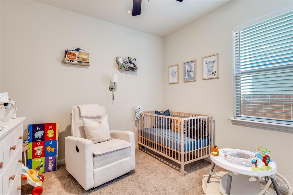 14240 Chaps Drive Dallas, TX 75253 - Photo 16 of 25 a bedroom with a baby bed a couch and a baby crib