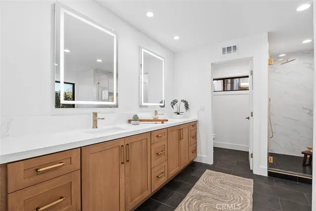 a spacious bathroom with a double vanity sink a mirror and a shower