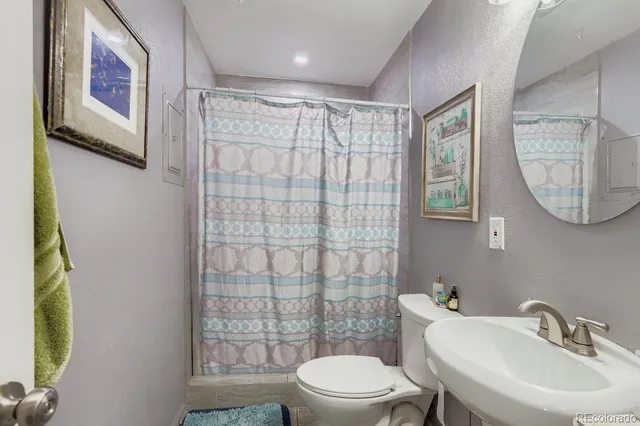 a bathroom with a toilet a sink a mirror and a shower