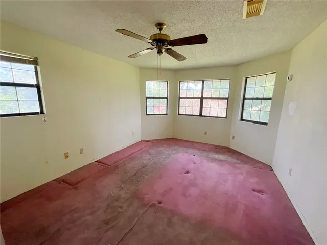 an empty room with windows and ceiling fan