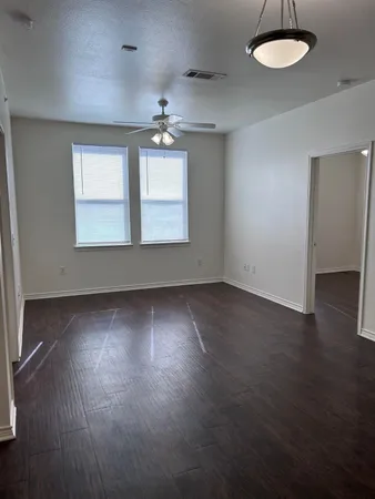 an empty room with wooden floor and windows