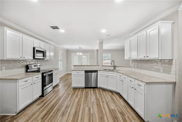 a kitchen with granite countertop white cabinets a sink dishwasher and a stove with wooden floor