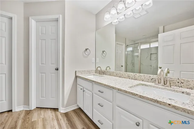 a spacious bathroom with a granite countertop sink a mirror and a shower