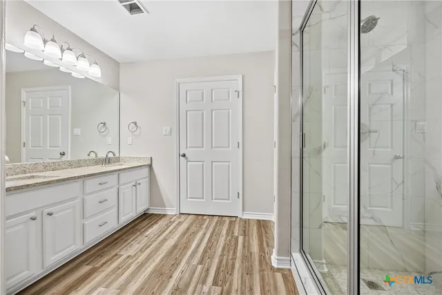 a spacious bathroom with a granite countertop sink a mirror and shower