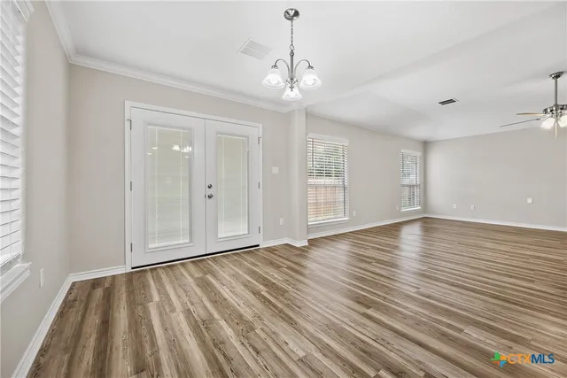 a view of an empty room with wooden floor and windows