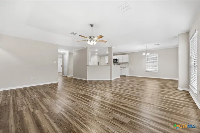 a view of a room with wooden floor and kitchen view